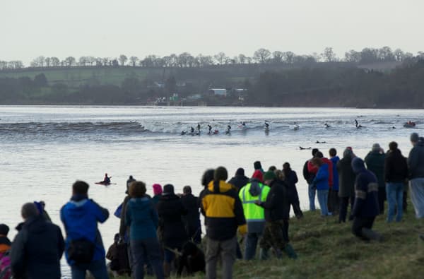 The Severn Bore from the shoreline with people surfing