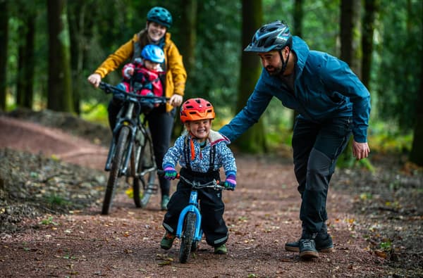 Family cycling and kids on bikes smilling in the Forest of Dean photo credit Forestry England