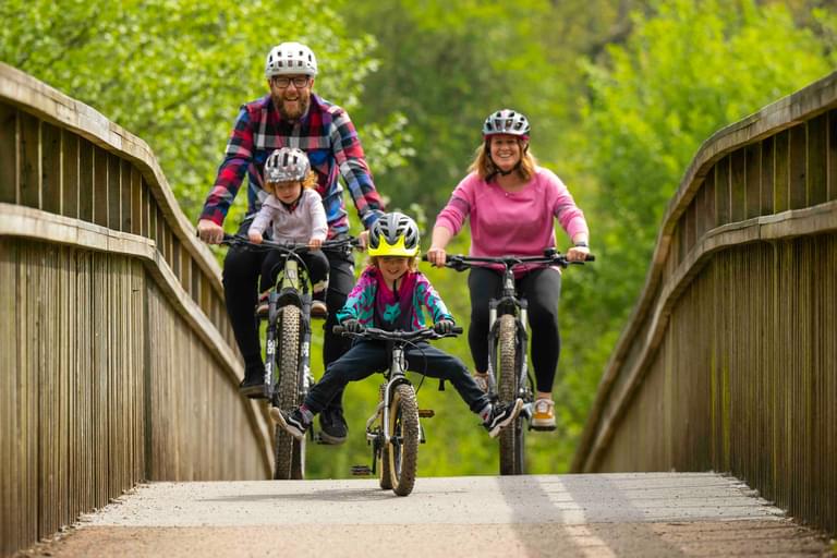 Family cycling over a bridge in the Forest of Dean photo credit Forestry England